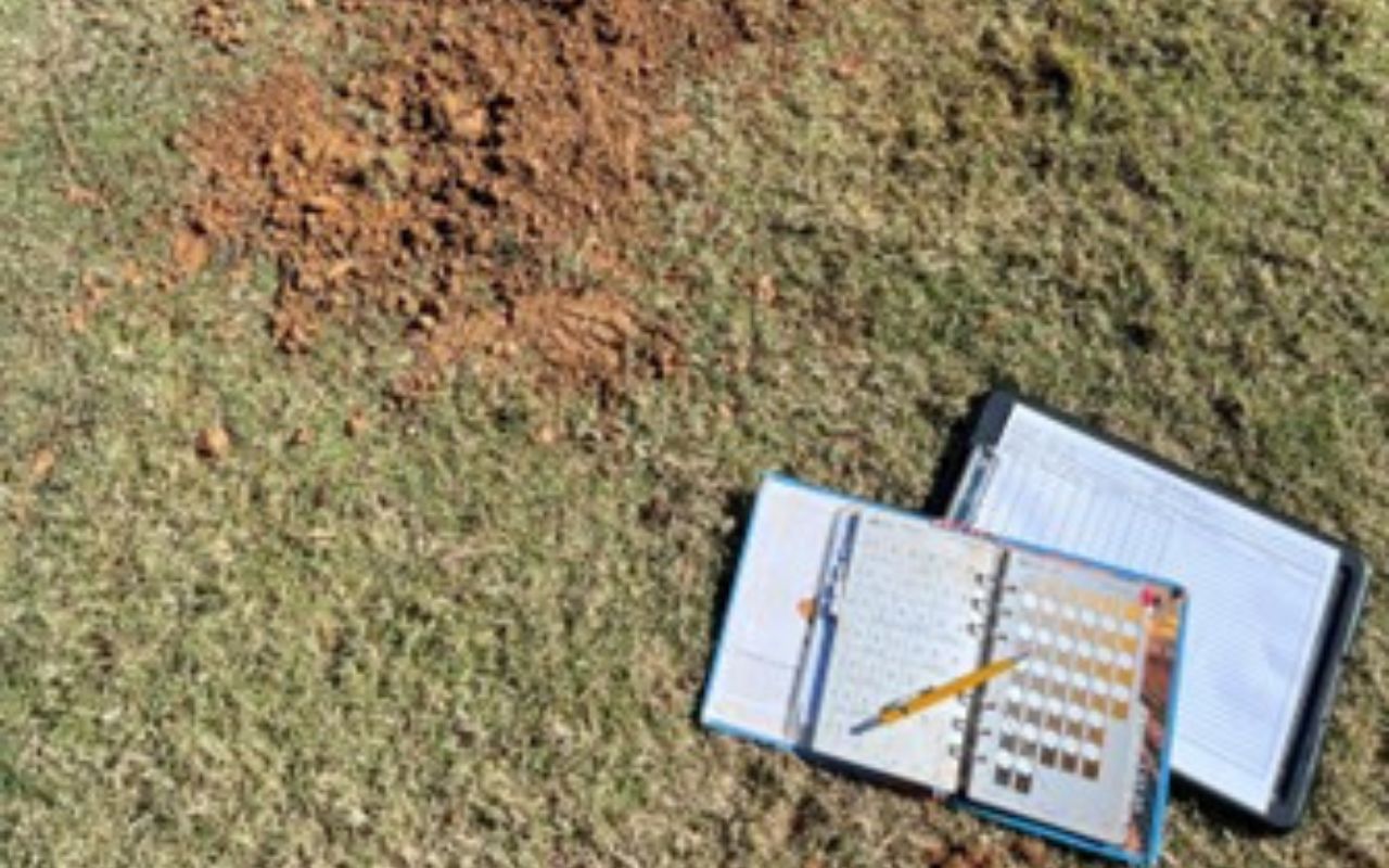 Binders and pens near dirt on the grass at the Subsurface Drip Dispersal project in Villa Rica, GA.